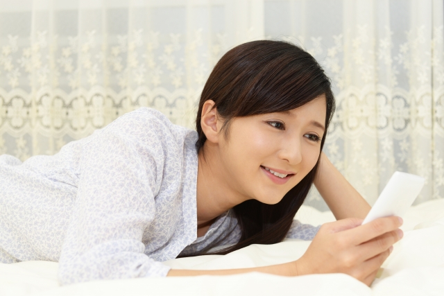 家のソファーでスマホを見る女性