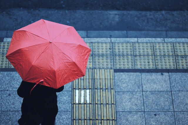 雨の中傘をさして信号待ちする女性