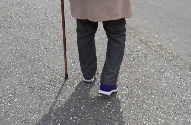 膝の痛みを庇って歩くシニア女性