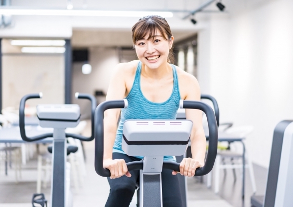 ジムでエアロバイクを漕ぐ女性