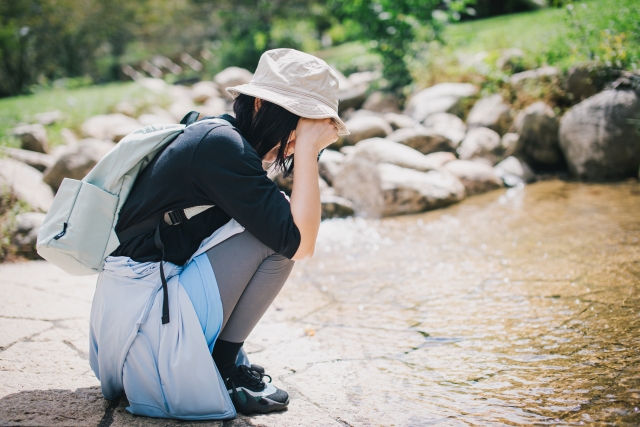 暑すぎて公園でしゃがみ込む女性