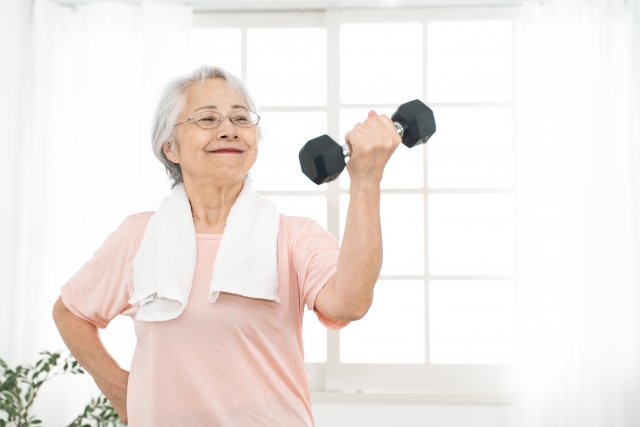 高齢の女性がダンベルを持ち自信満々にダンベルを持ち上げる画像