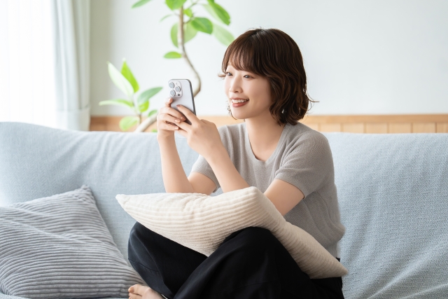 自宅でスマホを見ている女性