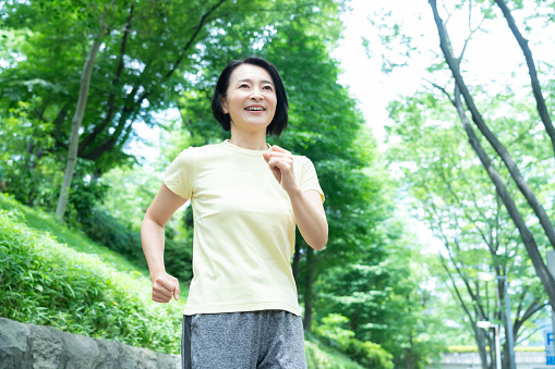 公園の中をウォーキングするミドル女性