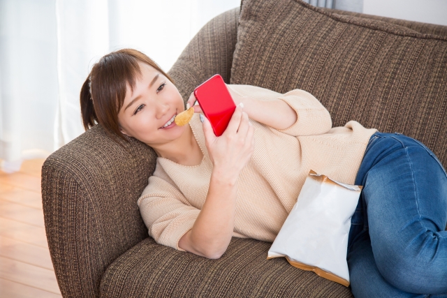 運動不足でゴロゴロソファーで過ごす女性。
