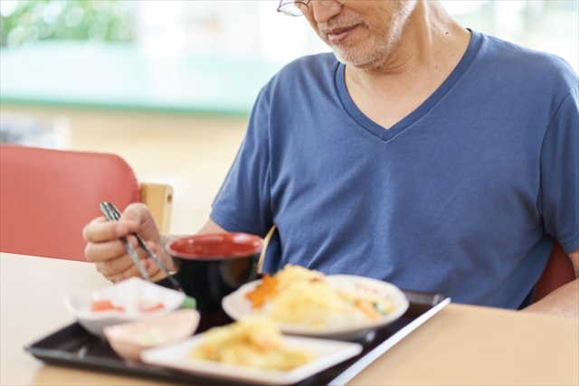一人で寂しく食事するシニア男性