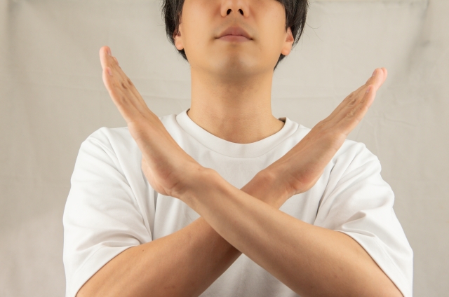 腕をバッテンにしてNGを出す男性