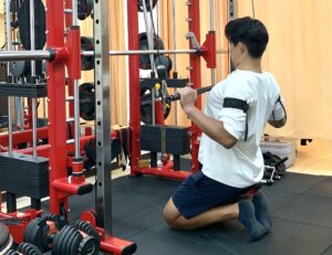 加圧ベルトをしながら背中の筋肉をトレーニングする男性メンバー。