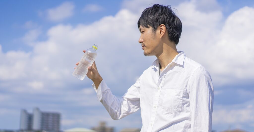 ウォーキング中にペットボトルの飲料水を飲む男性