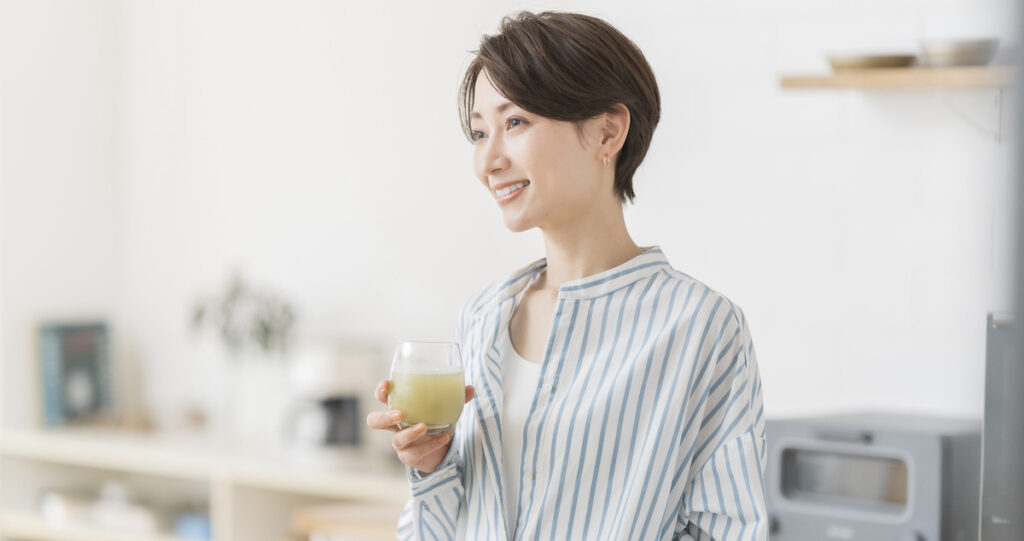 キッチンで飲み物を考えて摂取するミドル女性
